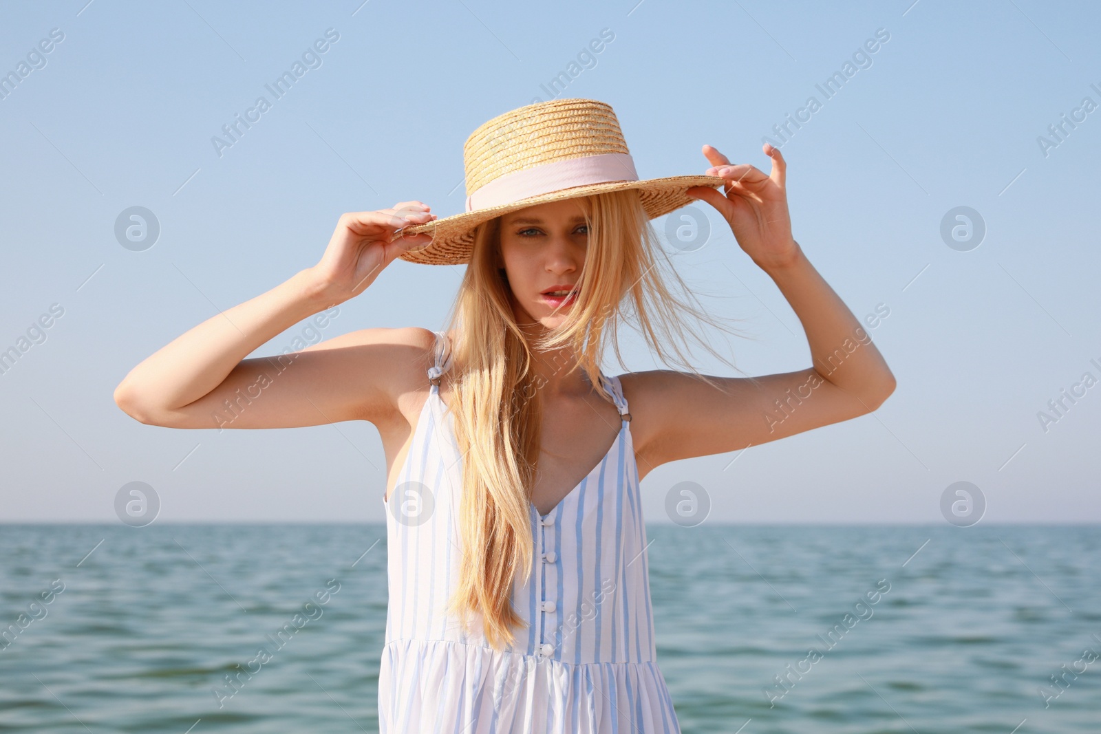 Beautiful young woman with straw hat near sea on sunny day in summer Photo of Beautiful young woman with straw hat near sea on sunny day in summer