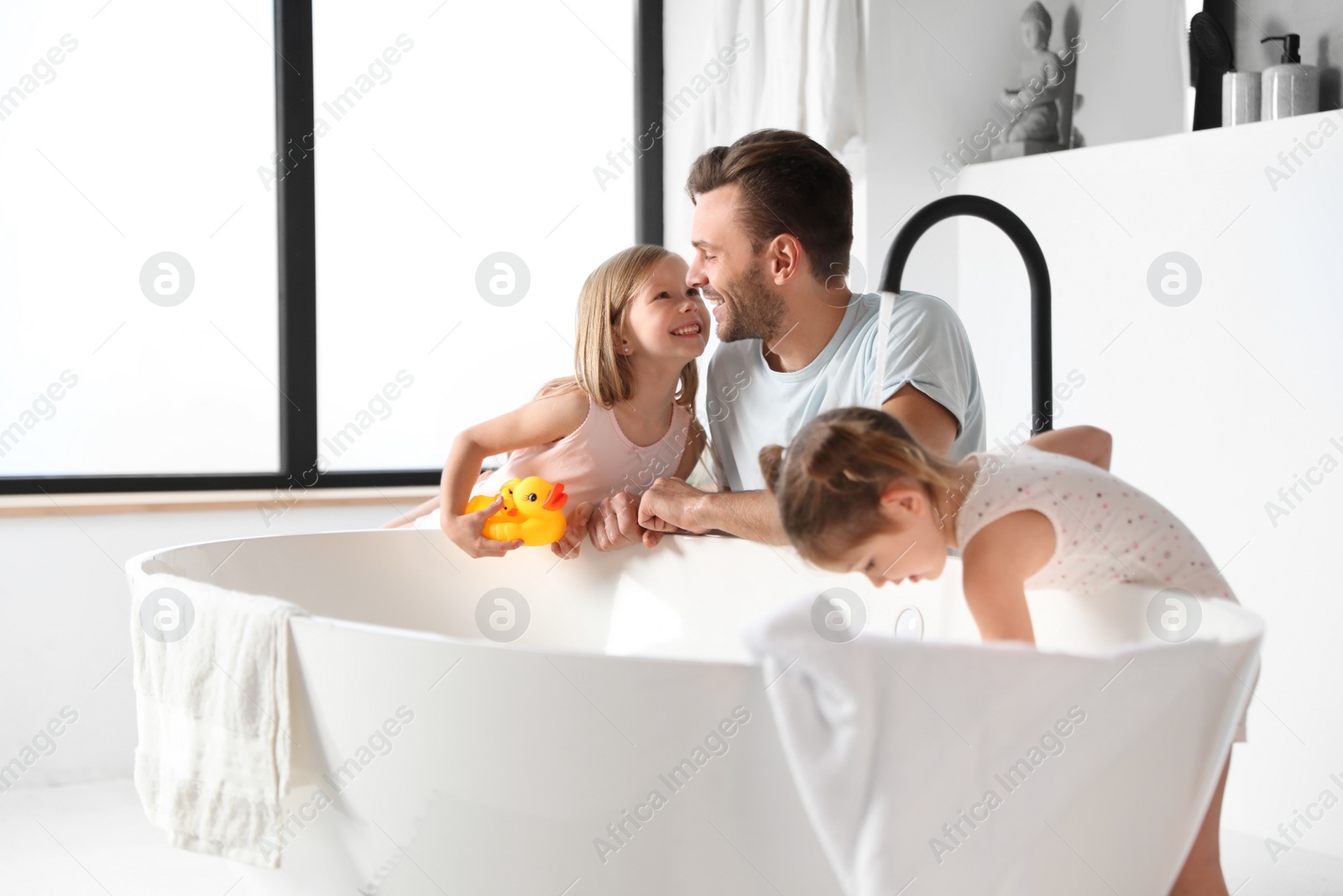 Photo of Young father with little daughters in bathroom