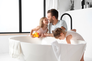 Photo of Young father with little daughters in bathroom