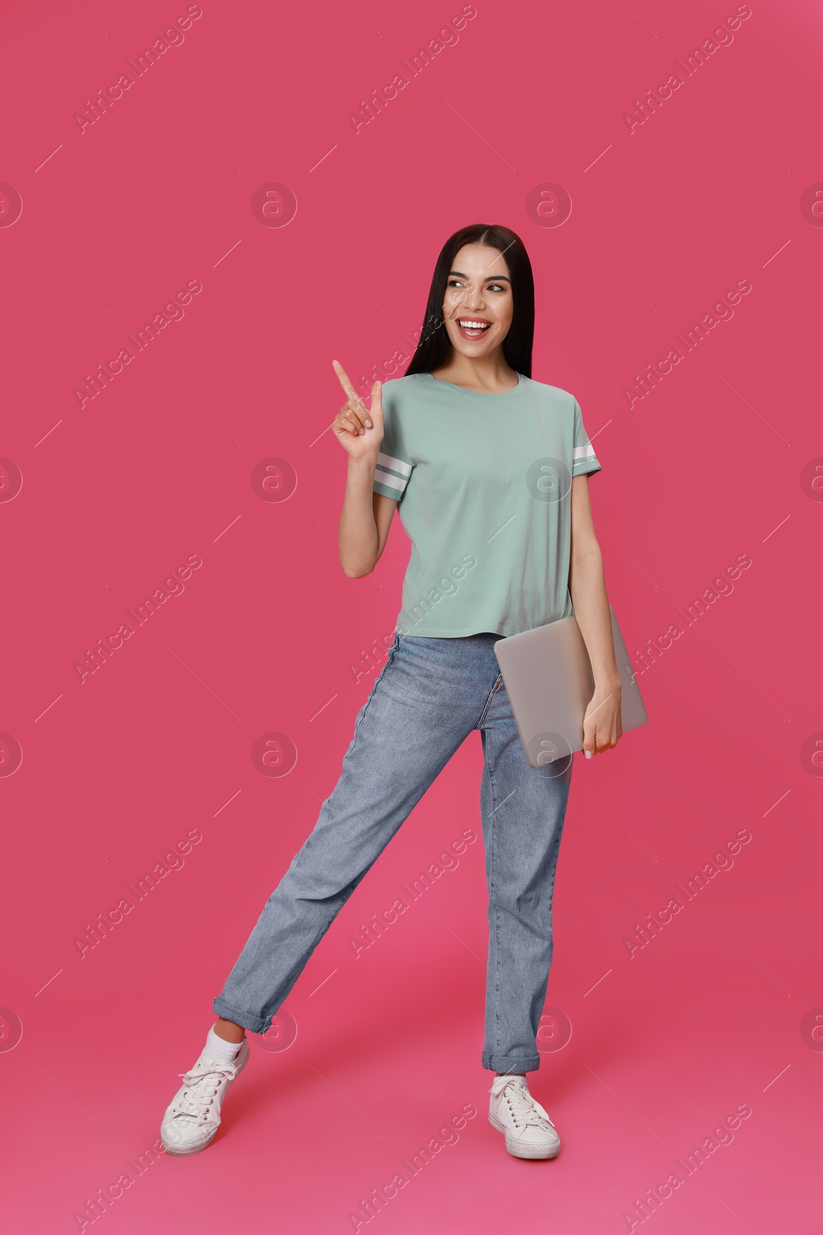 Young woman with modern laptop on pink background Photo of Young woman with modern laptop on pink background
