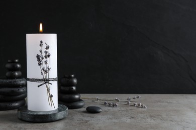 Burning candle with lavender and spa stones on grey table. Space for text Photo of Burning candle with lavender and spa stones on grey table. Space for text