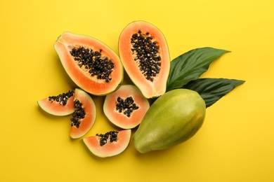 Fresh ripe papaya fruits with green leaves on yellow background, flat lay Photo of Fresh ripe papaya fruits with green leaves on yellow background, flat lay