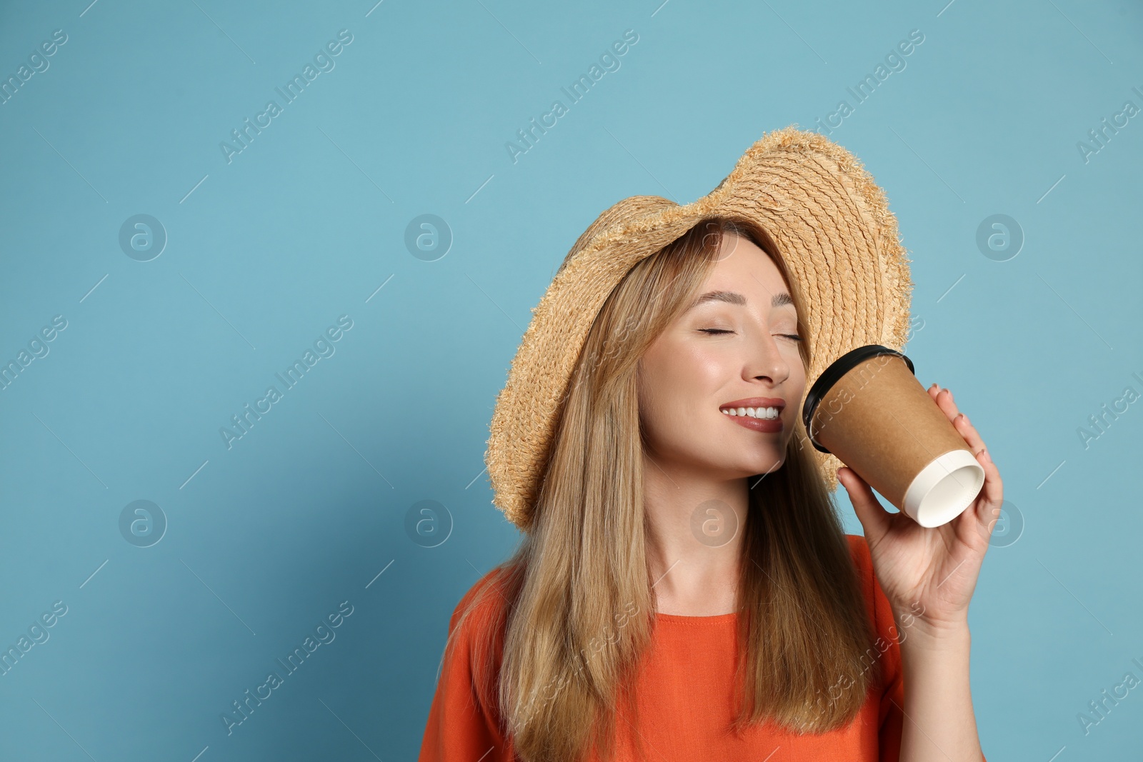 Beautiful young woman with straw hat drinking coffee from paper cup on light blue background, space for text. Stylish headdress Photo of Beautiful young woman with straw hat drinking coffee from paper cup on light blue background, space for text. Stylish headdress