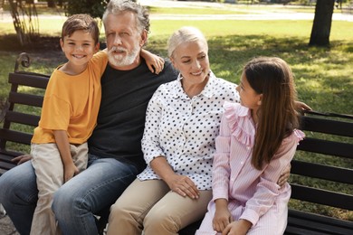 Happy grandparents with little children resting together in park Photo of Happy grandparents with little children resting together in park