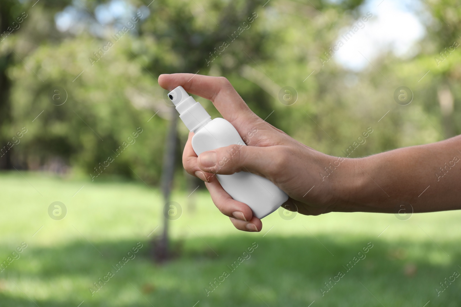 Woman with bottle of insect repellent spray outdoors, closeup Photo of Woman with bottle of insect repellent spray outdoors, closeup