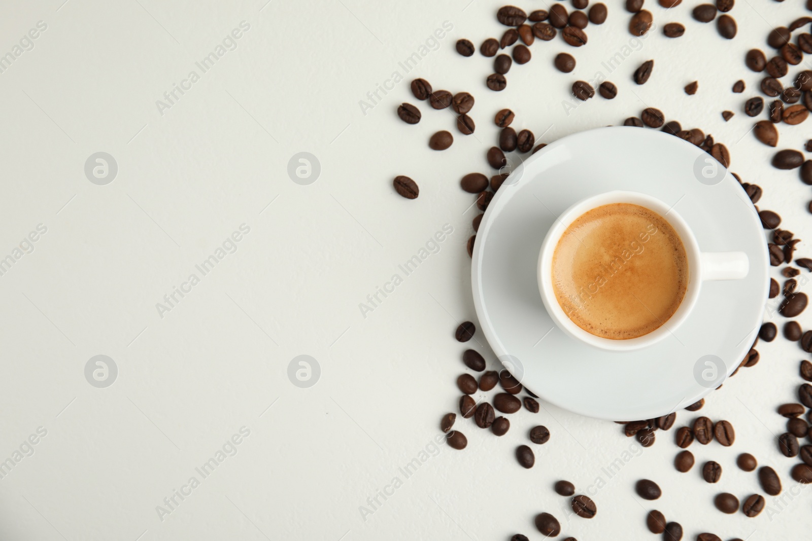Cup of hot aromatic espresso and roasted beans on white table, flat lay. Space for text Photo of Cup of hot aromatic espresso and roasted beans on white table, flat lay. Space for text
