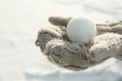 Woman in knitted mittens holding snowball outdoors, closeup Photo of Woman in knitted mittens holding snowball outdoors, closeup