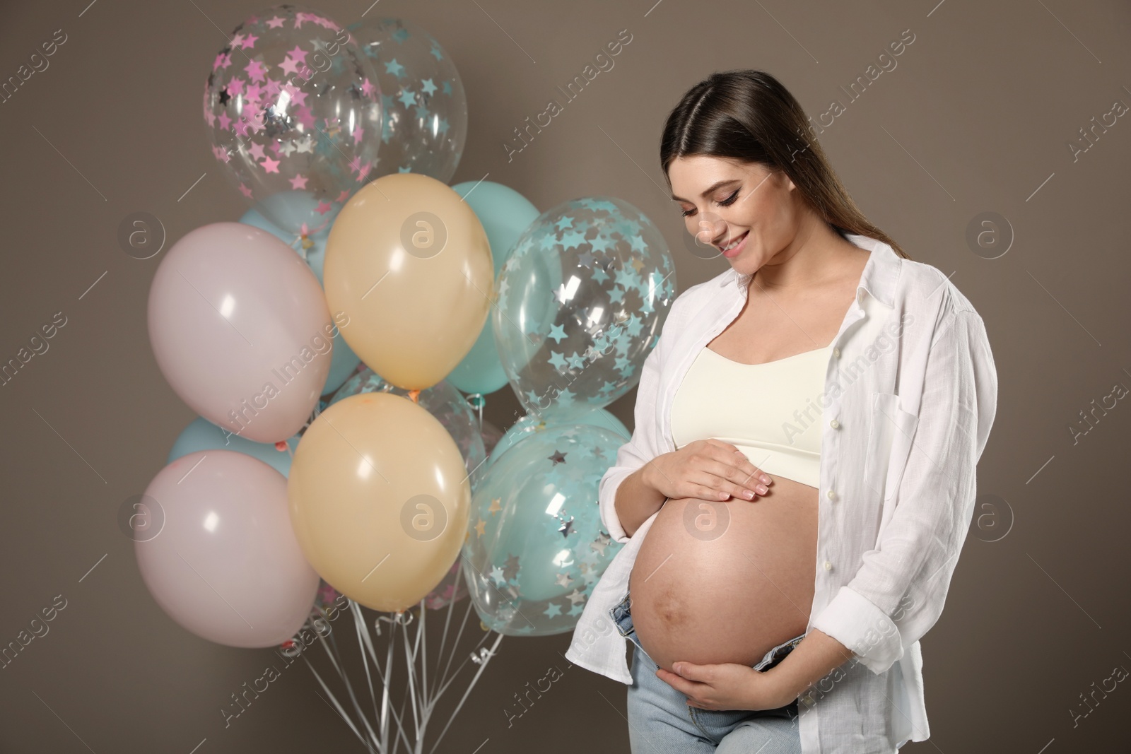 Happy pregnant woman with balloons near dark wall. Baby shower party Photo of Happy pregnant woman with balloons near dark wall. Baby shower party
