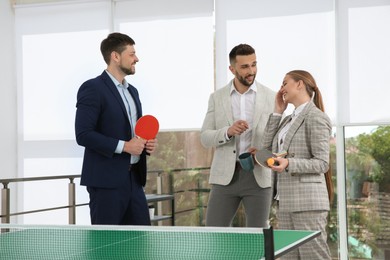 Business people talking near ping pong table in office Photo of Business people talking near ping pong table in office