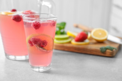 Jug and glass of fresh lemonade with berries on table Photo of Jug and glass of fresh lemonade with berries on table