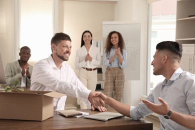 Employee shaking hand with new coworker in office Photo of Employee shaking hand with new coworker in office