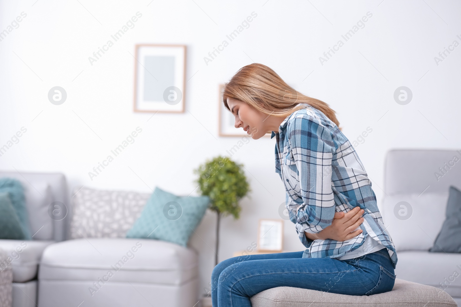 Photo of Young woman suffering from stomach ache at home