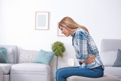 Photo of Young woman suffering from stomach ache at home