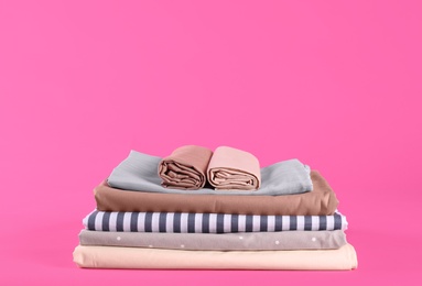 Stack of clean bed sheets on pink background. Space for text Photo of Stack of clean bed sheets on pink background. Space for text