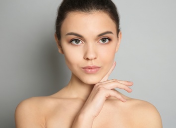Young woman with beautiful makeup on grey background. Professional cosmetic products Photo of Young woman with beautiful makeup on grey background. Professional cosmetic products