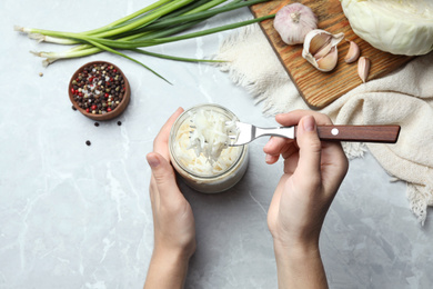 Woman eating fermented cabbage at light grey marble table, top view Photo of Woman eating fermented cabbage at light grey marble table, top view