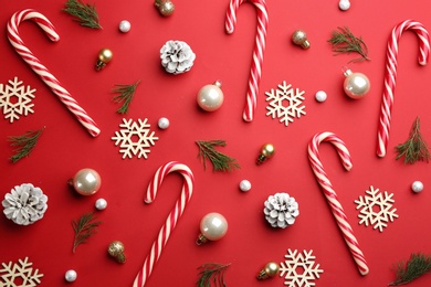 Photo of Flat lay composition with candy canes and Christmas decor on red background