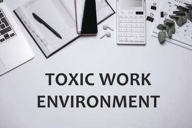 Laptop, smartphone, stationery and text TOXIC WORK ENVIRONMENT on white background, flat lay. Space for text Image of Laptop, smartphone, stationery and text TOXIC WORK ENVIRONMENT on white background, flat lay. Space for text