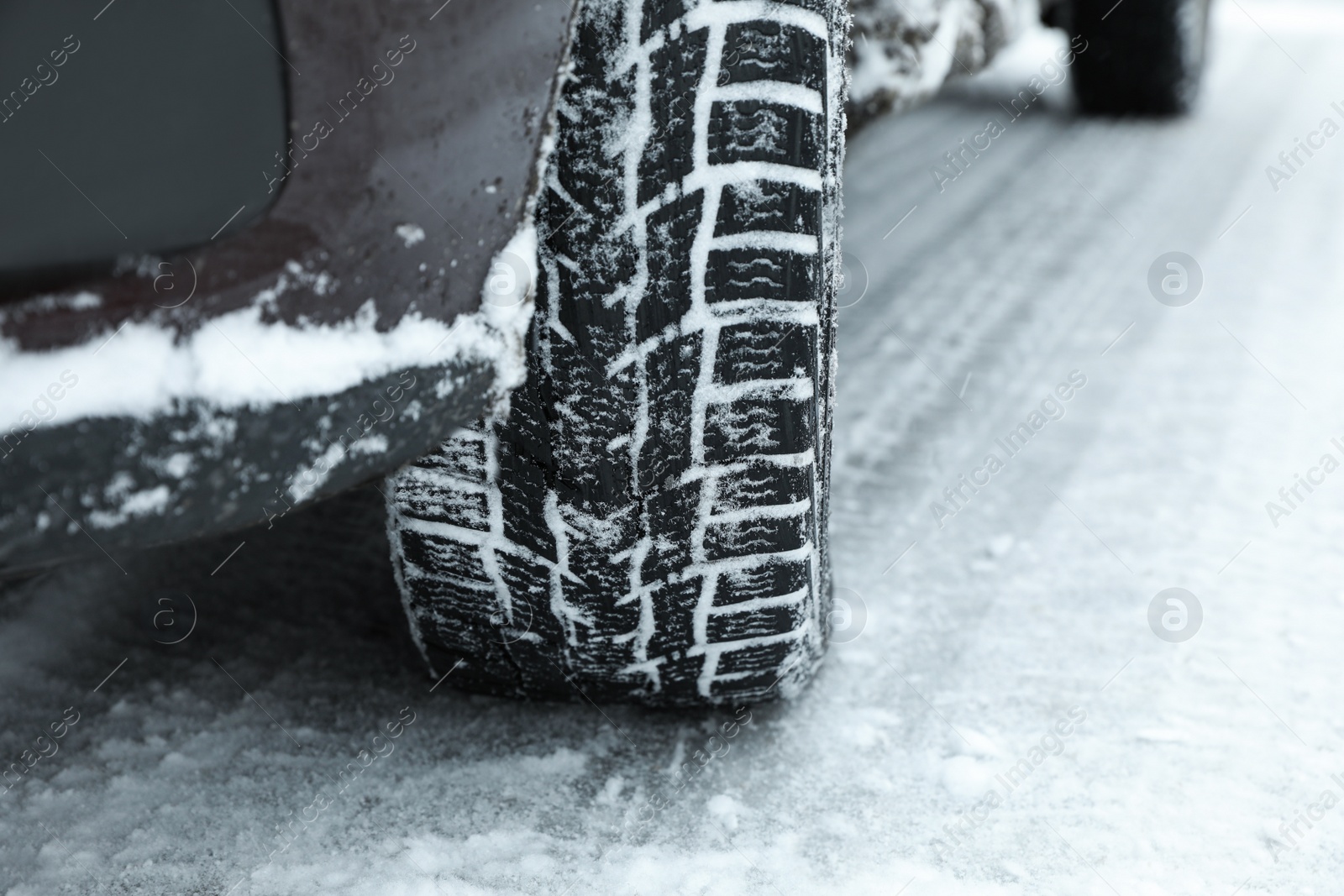 Modern car with winter tires on snowy road, closeup Photo of Modern car with winter tires on snowy road, closeup