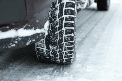 Modern car with winter tires on snowy road, closeup Photo of Modern car with winter tires on snowy road, closeup
