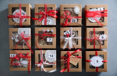 Set of gift boxes with Christmas decor on light grey stone table, flat lay. Advent calendar Photo of Set of gift boxes with Christmas decor on light grey stone table, flat lay. Advent calendar