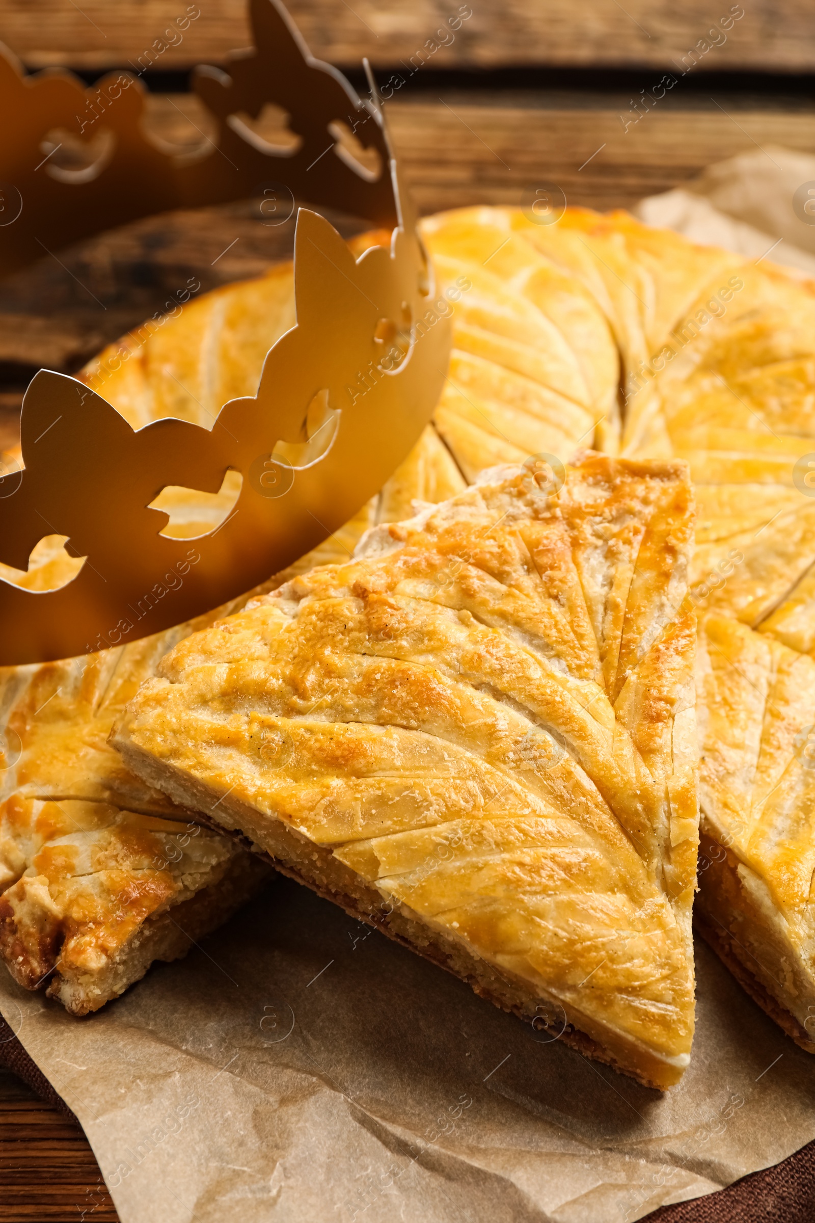 Traditional galette des Rois with paper crown on wooden table, closeup Photo of Traditional galette des Rois with paper crown on wooden table, closeup