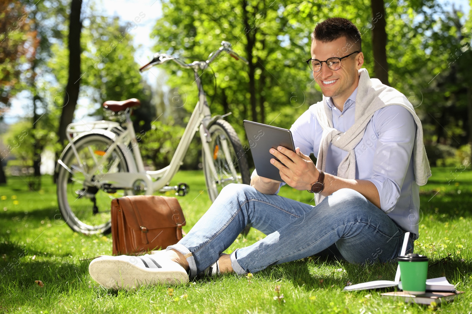 Man working with tablet on grass in park Photo of Man working with tablet on grass in park