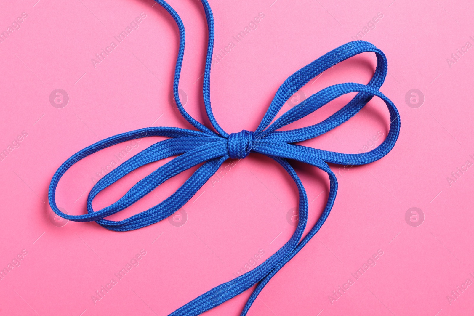 Blue shoelaces on pink background, top view Photo of Blue shoelaces on pink background, top view
