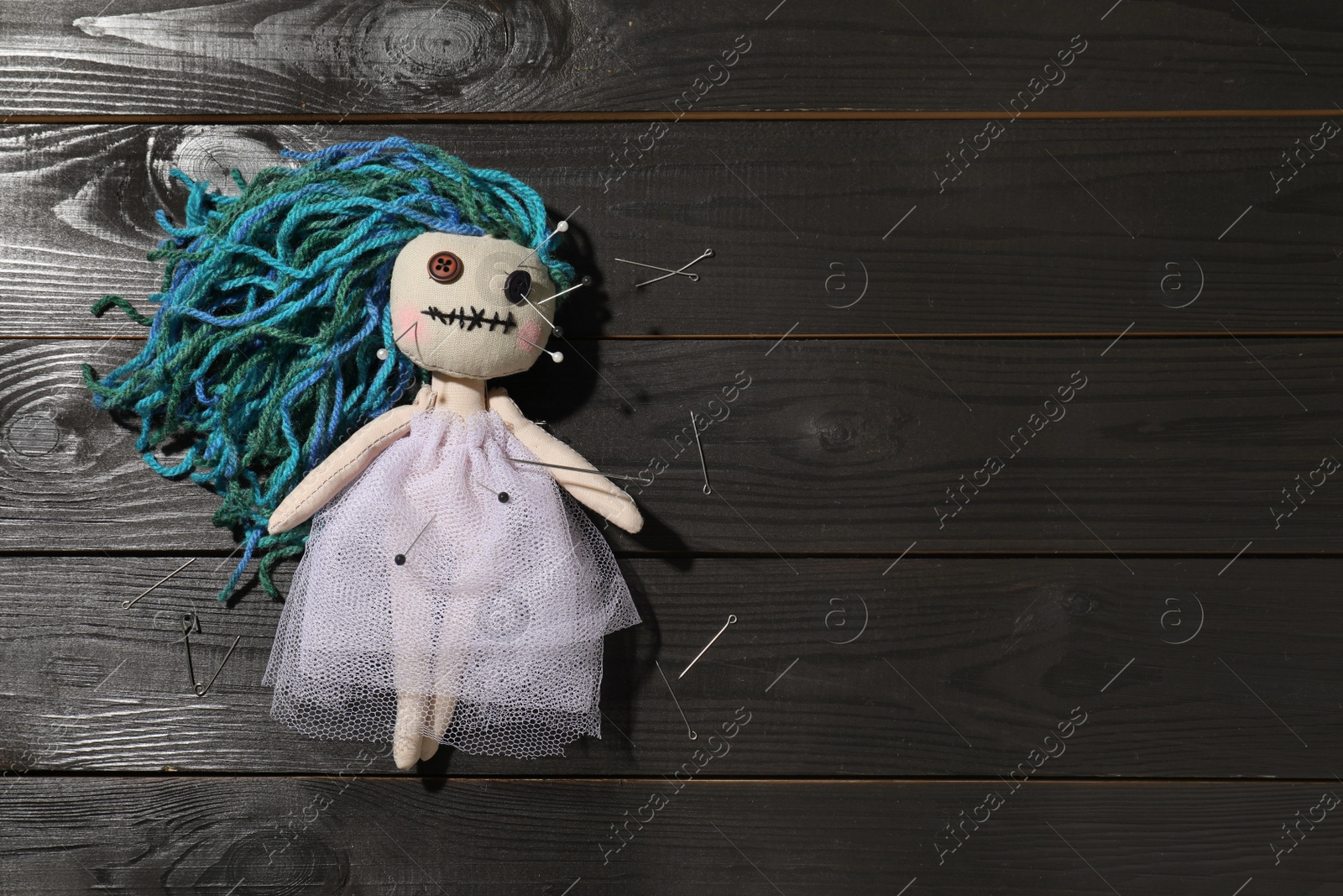 Female voodoo doll with pins on wooden background, flat lay. Space for text Photo of Female voodoo doll with pins on wooden background, flat lay. Space for text
