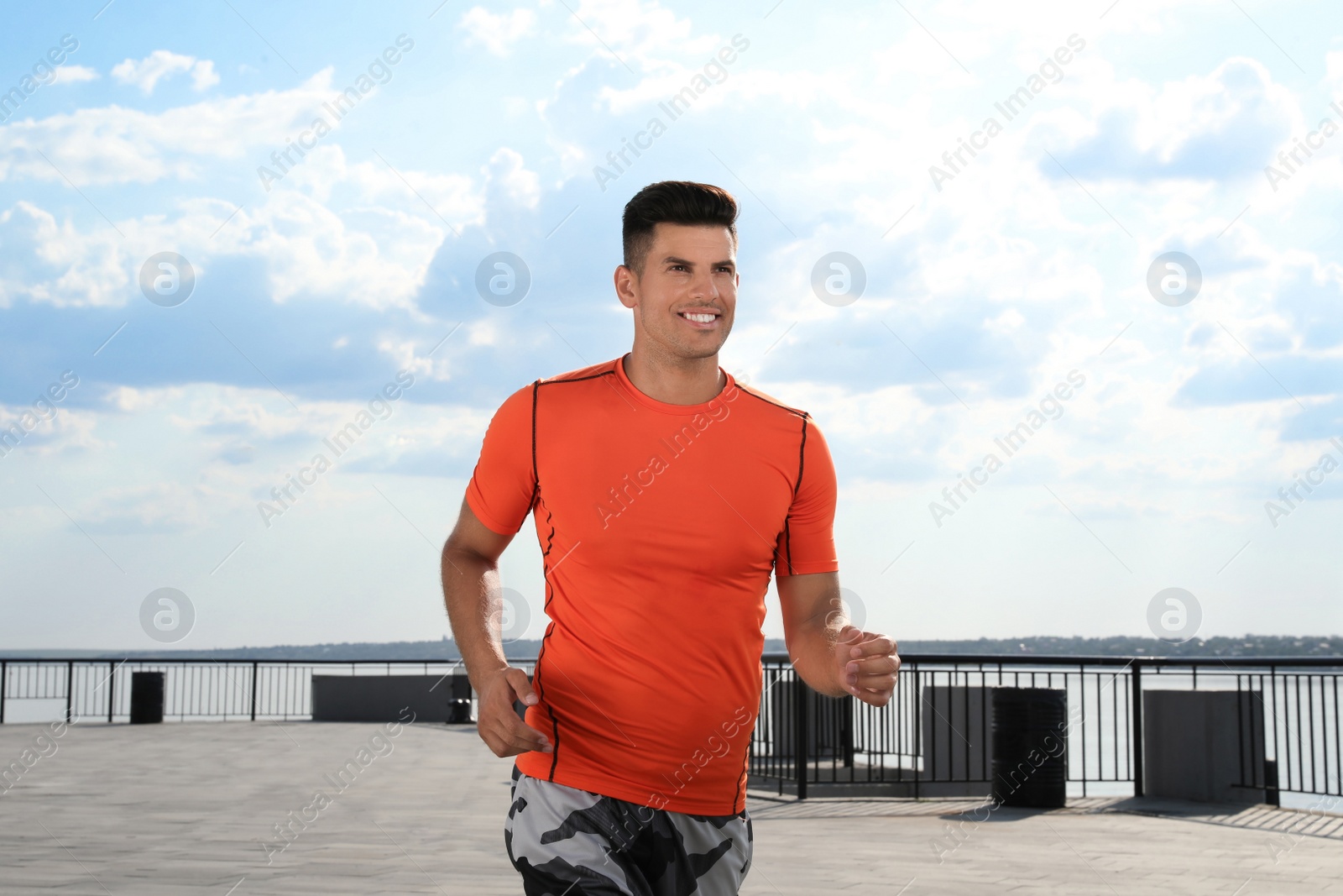 Handsome man in sportswear running outdoors on sunny day Photo of Handsome man in sportswear running outdoors on sunny day