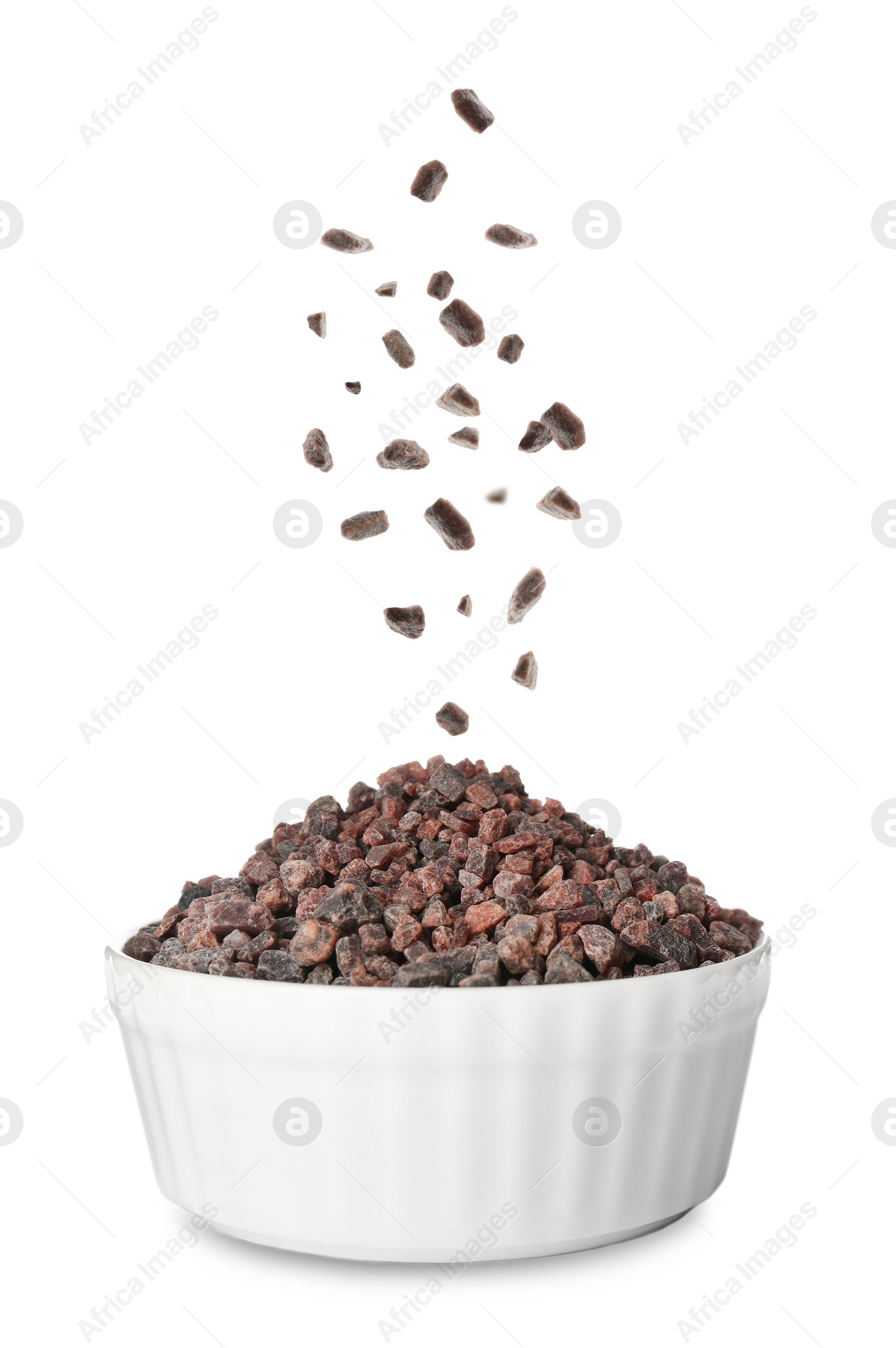 Black salt crystals falling into bowl on white background Image of Black salt crystals falling into bowl on white background