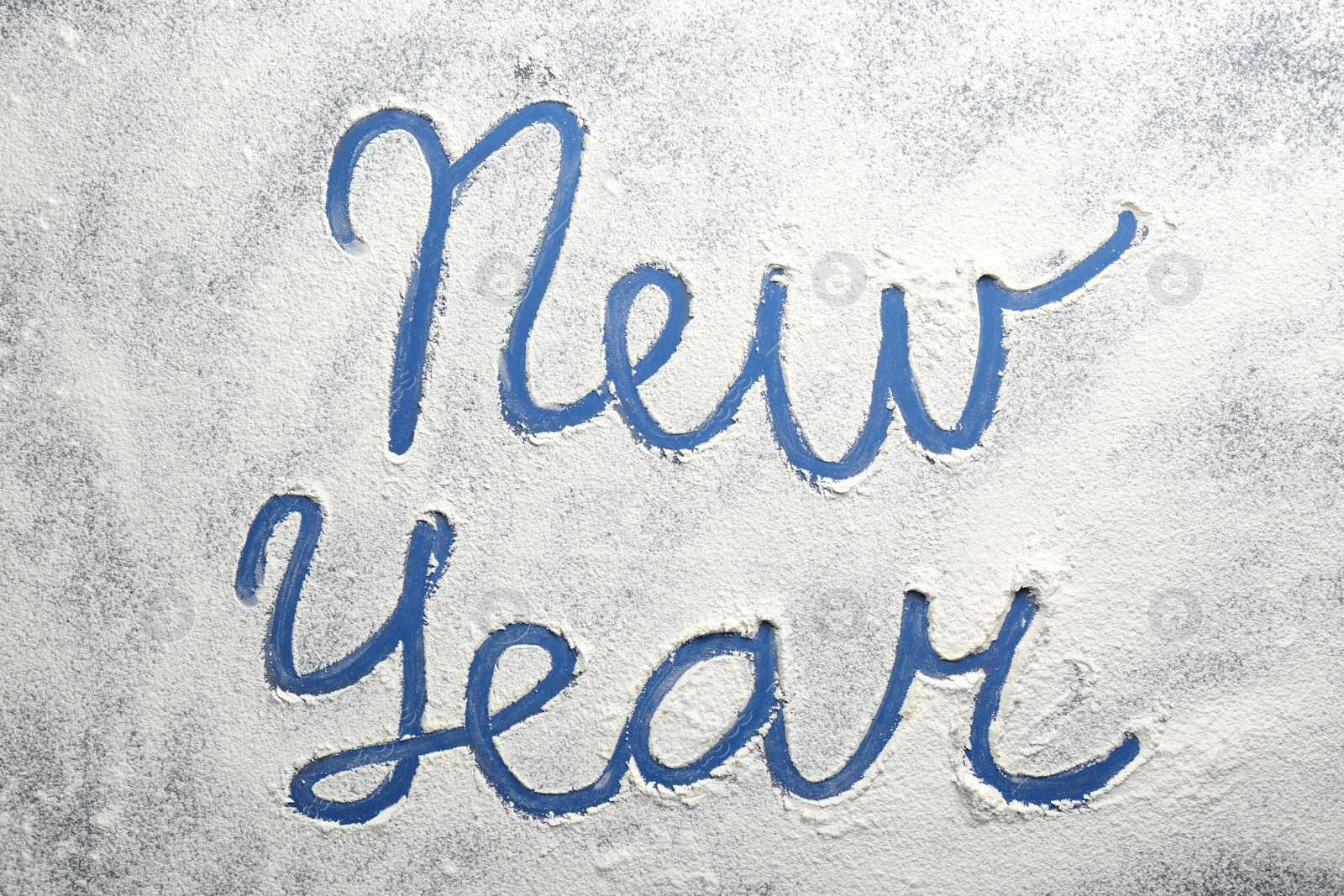 Words New Year made of flour on blue background, top view Photo of Words New Year made of flour on blue background, top view