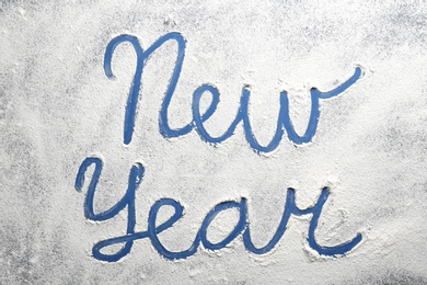 Words New Year made of flour on blue background, top view Photo of Words New Year made of flour on blue background, top view
