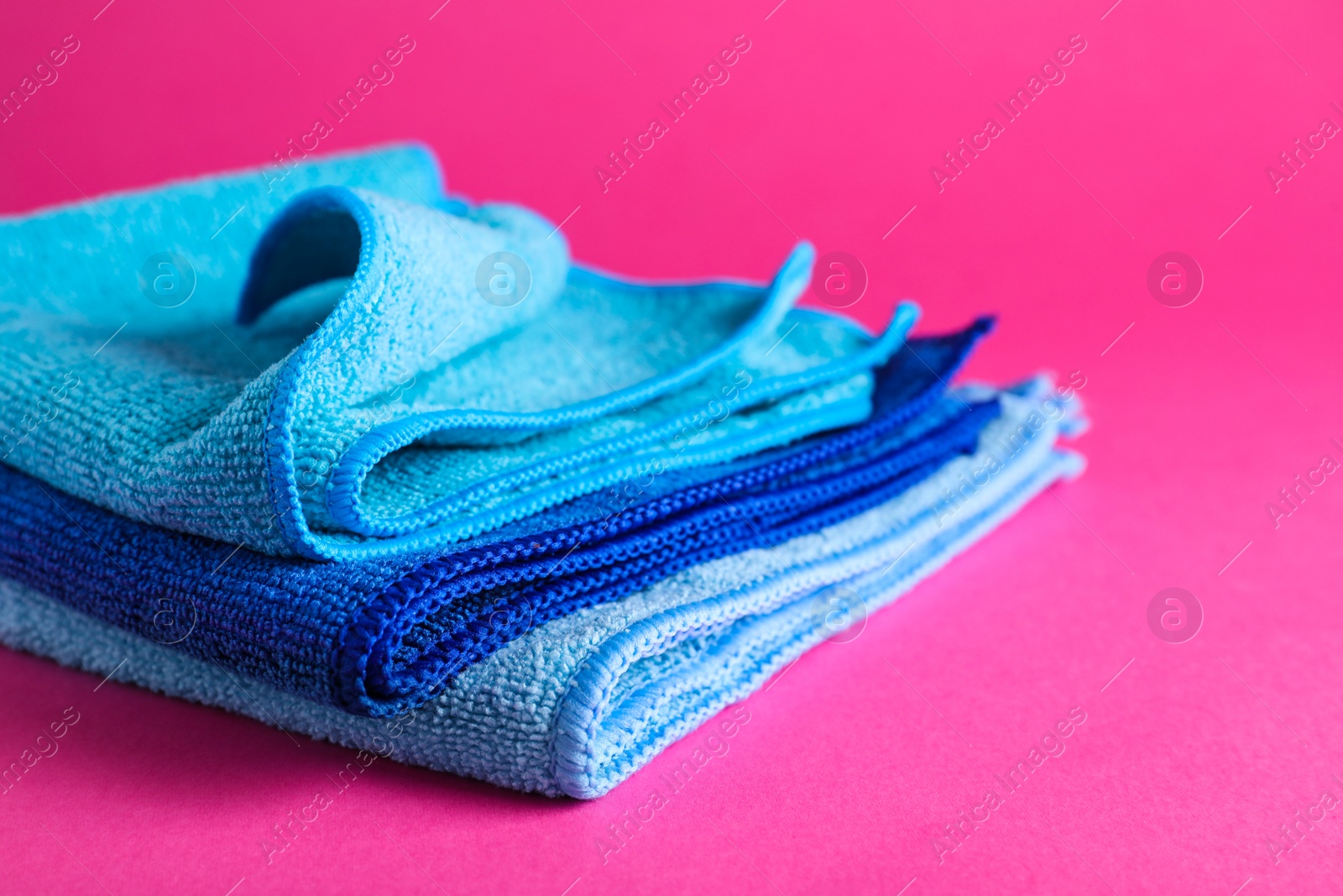 Stack of blue microfiber cloths on pink background, closeup Photo of Stack of blue microfiber cloths on pink background, closeup