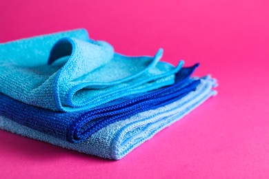 Stack of blue microfiber cloths on pink background, closeup Photo of Stack of blue microfiber cloths on pink background, closeup