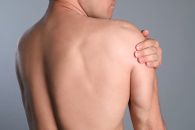 Man suffering from shoulder pain on grey background, closeup Photo of Man suffering from shoulder pain on grey background, closeup