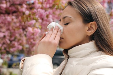 Woman suffering from seasonal pollen allergy near blossoming tree outdoors Photo of Woman suffering from seasonal pollen allergy near blossoming tree outdoors