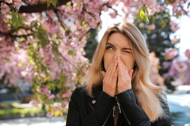 Woman suffering from seasonal pollen allergy near blossoming tree outdoors Photo of Woman suffering from seasonal pollen allergy near blossoming tree outdoors