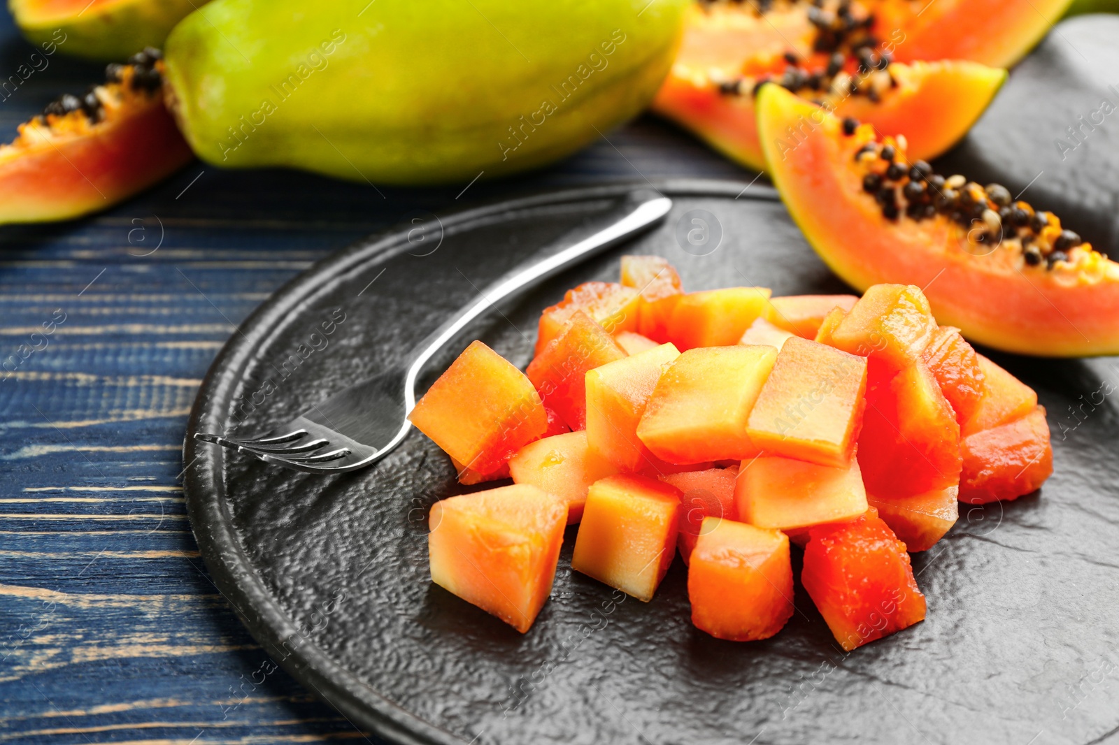 Diced fresh ripe papaya with fork on wooden table Photo of Diced fresh ripe papaya with fork on wooden table
