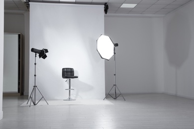 Photo of Photo studio interior with modern chair and professional lighting equipment