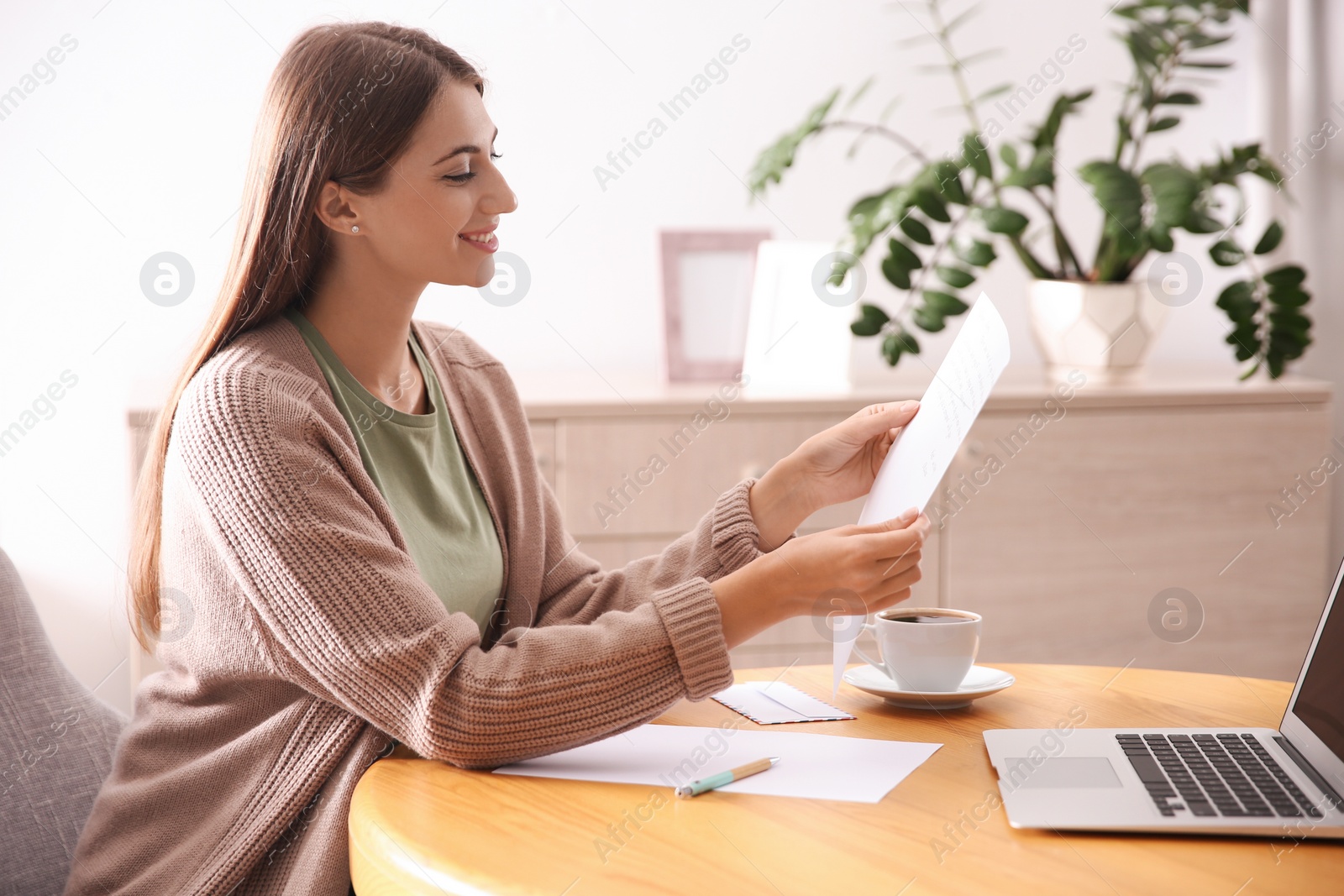 Woman reading letter at wooden table in room Photo of Woman reading letter at wooden table in room