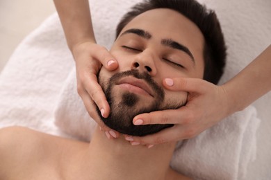 Young man receiving facial massage in beauty salon, above view Photo of Young man receiving facial massage in beauty salon, above view
