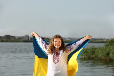 Teenage girl in vyshyvanka with flag of Ukraine outdoors Photo of Teenage girl in vyshyvanka with flag of Ukraine outdoors