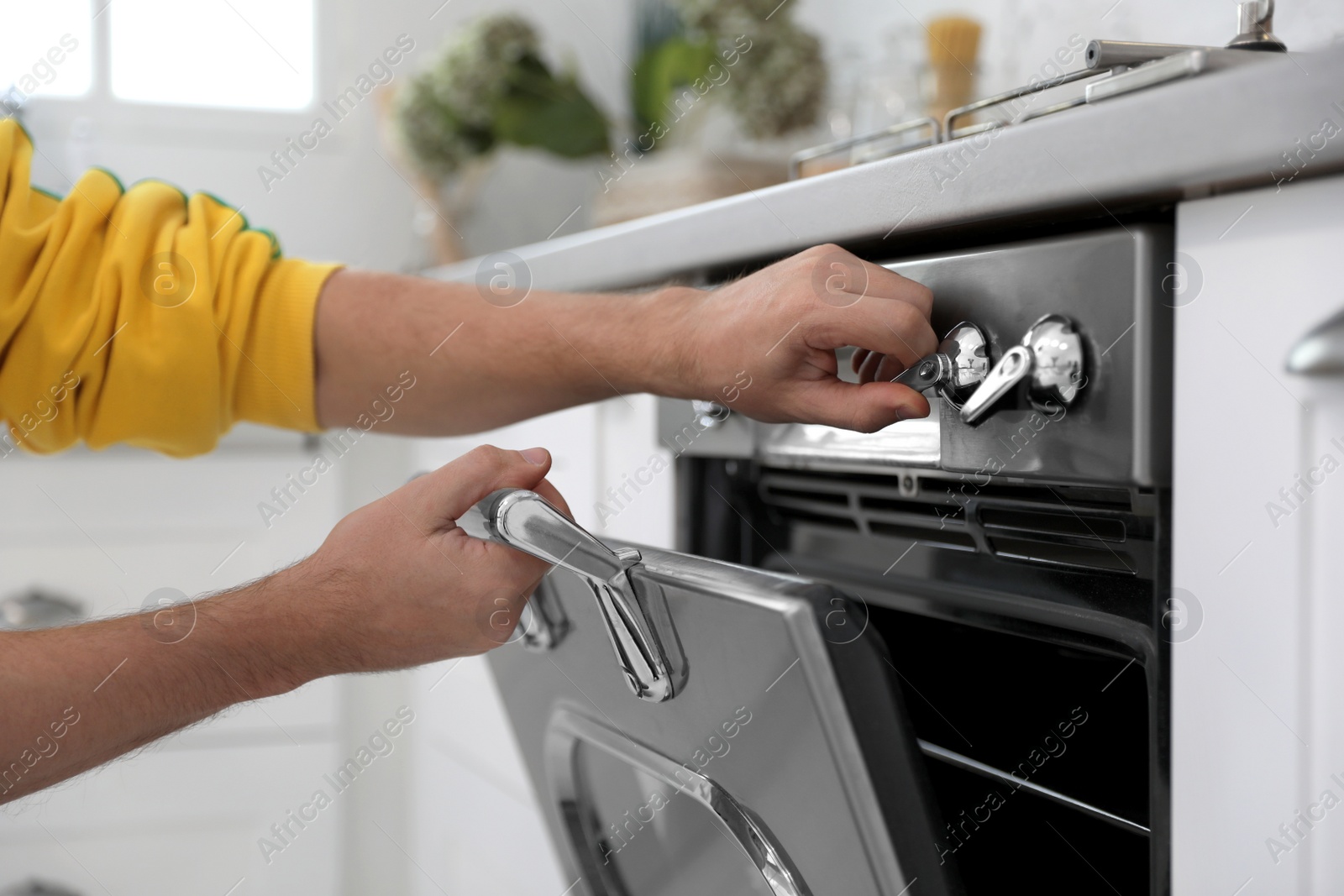 Man using modern oven in kitchen, closeup Photo of Man using modern oven in kitchen, closeup