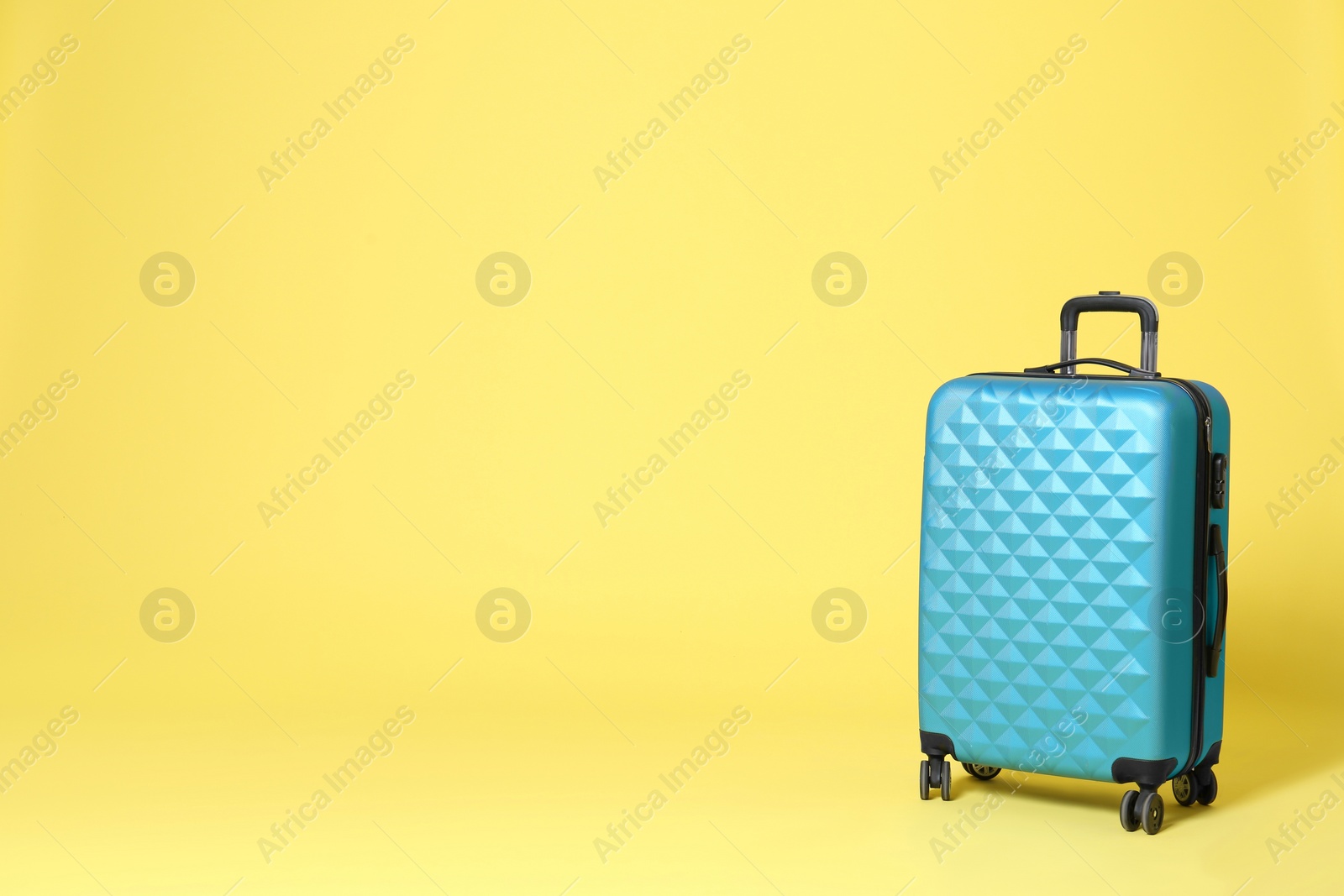Stylish blue suitcase on yellow background. Space for text Photo of Stylish blue suitcase on yellow background. Space for text