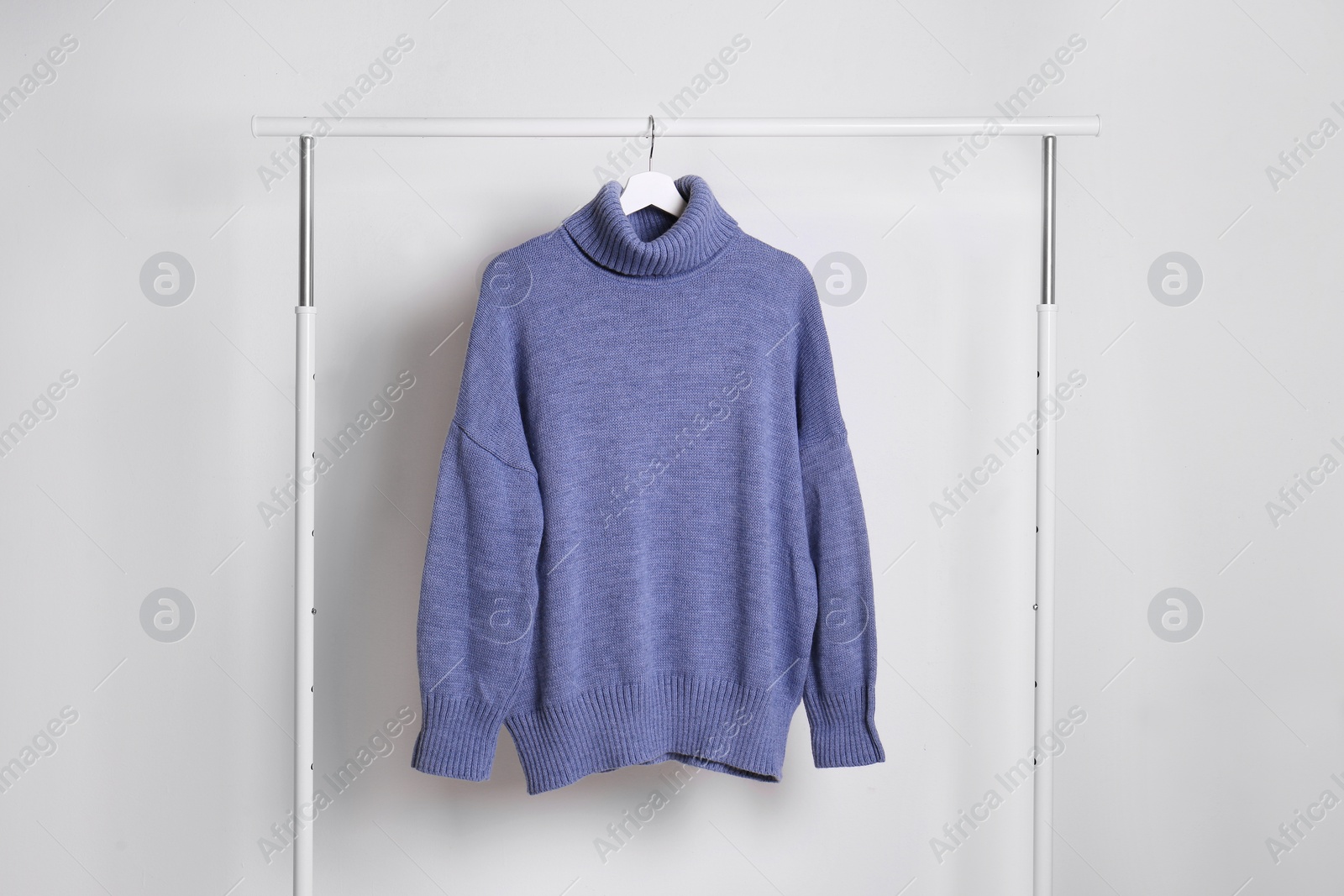 Warm sweater hanging on rack against white background Photo of Warm sweater hanging on rack against white background