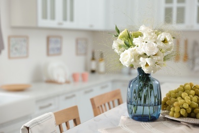 Bouquet of beautiful eustoma flowers and grapes on white table in kitchen. Interior design Photo of Bouquet of beautiful eustoma flowers and grapes on white table in kitchen. Interior design