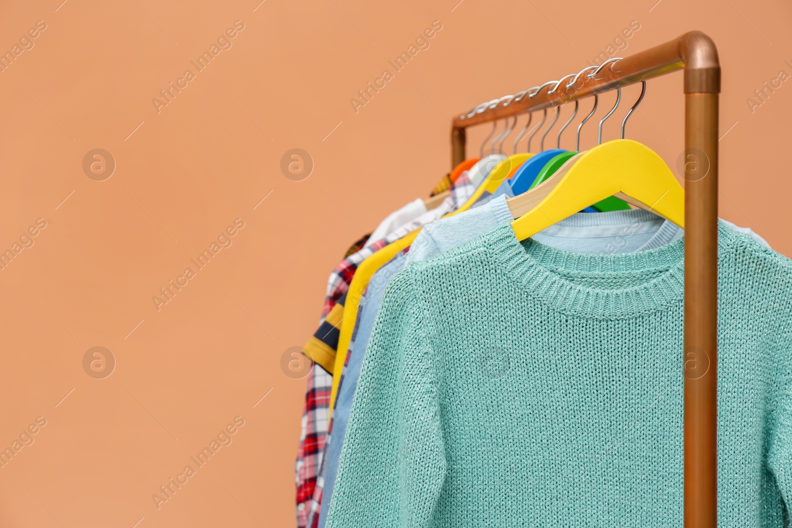 Rack with stylish children clothes on beige background, closeup. Space for text Photo of Rack with stylish children clothes on beige background, closeup. Space for text