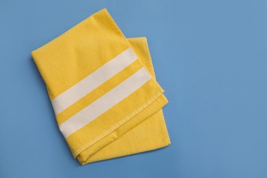 Folded yellow beach towel on blue background, top view. Space for text Photo of Folded yellow beach towel on blue background, top view. Space for text