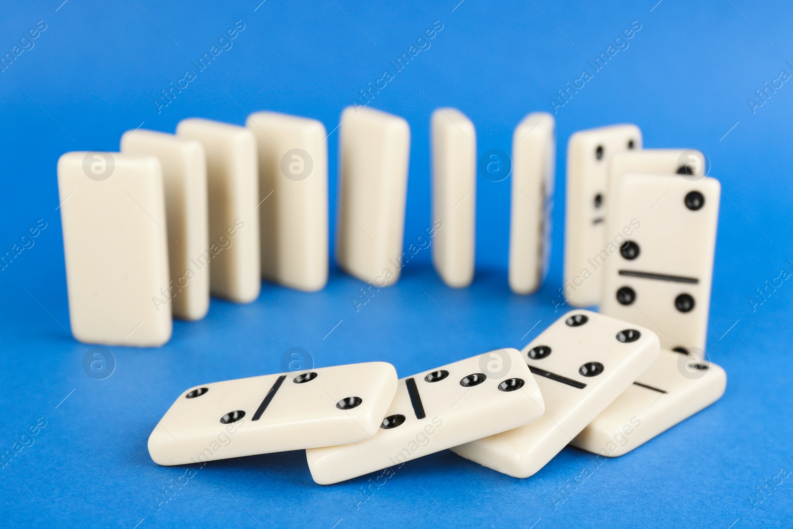 White domino tiles falling on blue background Photo of White domino tiles falling on blue background